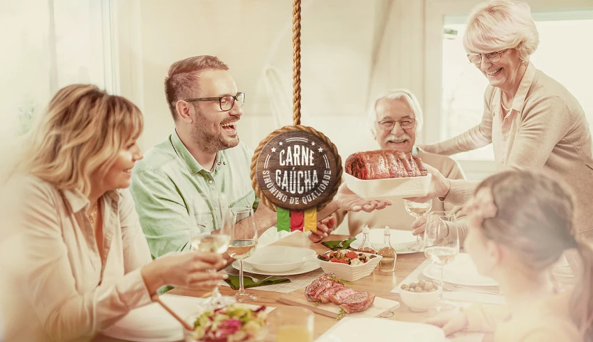 Peça da campanha: casal preparando carne na cozinha, com a assinatura “Sabor da nossa tradição”.