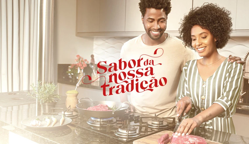 Peça da campanha: família reunida à mesa recebendo uma peça de carne assada, com o selo Carne Gaúcha.